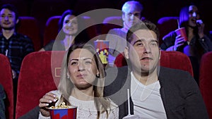 A couple watching a melodrama, eating popcorn and drinking a cola.