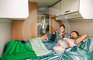 Couple watching a movie on the tablet lying on the bed of their camper van