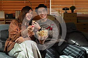 Couple watching moving, television streaming services while sitting on a Couch in the living room