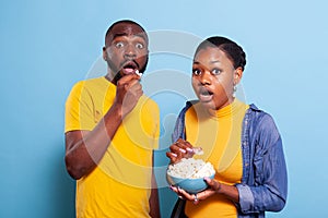 Couple watching scary movie on tv and eating popcorn