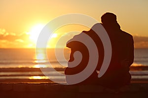 Couple watching sunset on the beach in winter