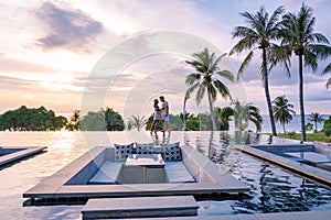 couple watching sunset in infinity pool on a luxury vacation in Thailand, man and woman watching sunset on the edge of a