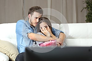 Couple watching terror tv movie at home photo