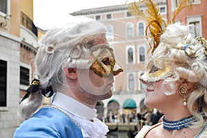 Couple watching themselves dressed up for Venice Carnival wearing contemporary clothes