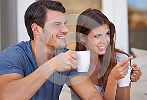 Couple, watching tv and point with coffee on sofa for questions, conversation or choice in home. People, man and woman