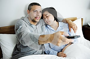 A couple watching tv together in bed