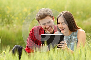 Couple watching videos in a tablet in a field photo