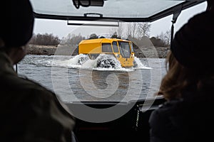 Couple watching at a yellow off-roader crossing a river