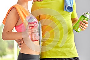 Couple with water bottles and towel in gym