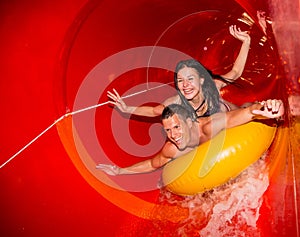 Couple in water slide at public swimming pool