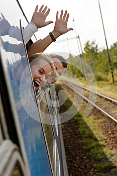 Couple waving with heads out train window