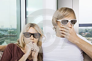 Couple wearing 3D glasses and watching TV with concentration at home