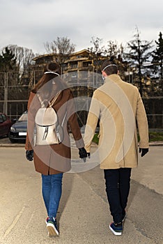 Couple wearing black nitrile gloves and masks walking on the street and holding their hands