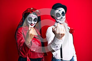 Couple wearing day of the dead costume over red beckoning come here gesture with hand inviting welcoming happy and smiling