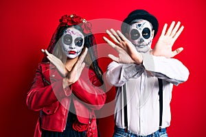 Couple wearing day of the dead costume over red rejection expression crossing arms doing negative sign, angry face