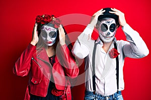 Couple wearing day of the dead costume over red suffering from headache desperate and stressed because pain and migraine