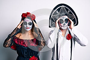 Couple wearing day of the dead costume over white with hand on head, headache because stress