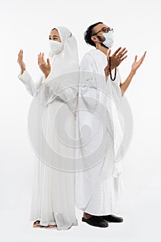 Couple wearing hajj ihram clothes praying with hands looking up