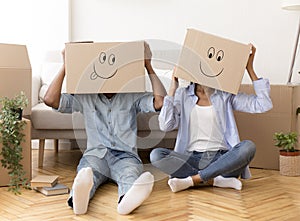 Couple Wearing Moving Boxes On Head Sitting On Floor Indoor