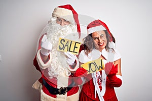 Couple wearing Santa costume holding wow and sale banner over isolated white background Beckoning come here gesture with hand