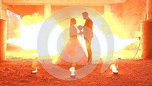 Couple in wedding attire with a terrible makeup, on background burns a huge fire