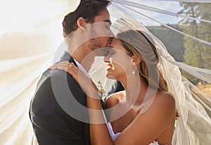 Couple, wedding and forehead kiss with vail for love, compassion or affection together in nature. Marred man kissing