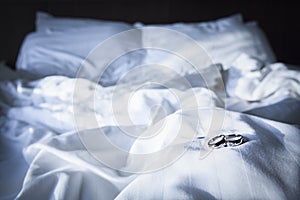 Couple wedding ring on wrinkly blanket on bed in valentine day.