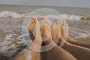 Couple wet feet in sand close up on sunny beach with waves. Couple in love relaxing together on sandy seashore. Family summer