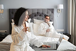 Couple in white bathrobe on a bed in a hotel.