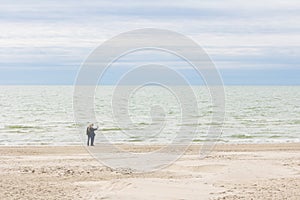 Couple on white sand beach with sea in background.