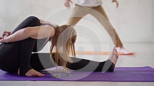 Couple in white yoga studio. sporty flexible woman in black sportswear practicing yoga in yoga class