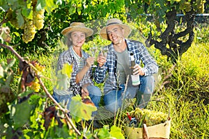 Couple of winegrowers tasting white wine in vineyard