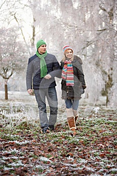 Couple On Winter Walk Through Frosty Landscape