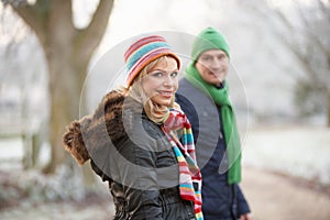 Couple On Winter Walk Through Frosty Landscape