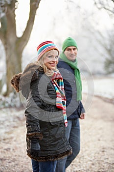 Couple On Winter Walk Through Frosty Landscape