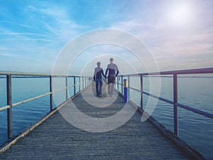 Couple woamn and man silhouettes walk on wharf pier above sea