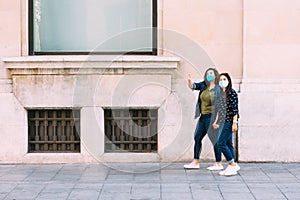Couple of women with a face mask walking hand in hand