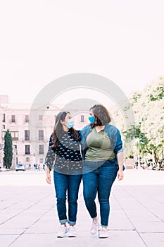 Couple of women with a face mask walking hand in hand