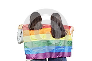 Couple of women holding a gay LGBT rainbow flag over their shoulders