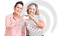 Couple of women wearing casual clothes smiling in love showing heart symbol and shape with hands