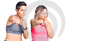 Couple of women wearing sportswear punching fist to fight, aggressive and angry attack, threat and violence