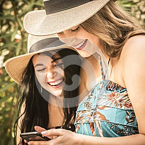 Couple of women young friends have fun together using cellular phone connection in outdoor - concept of girlfriend and lesbian