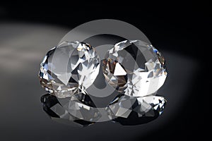 Couple of wonderful pure diamonds with reflections on black mirror background close up view. Jewelry diamonds sale, invitation,