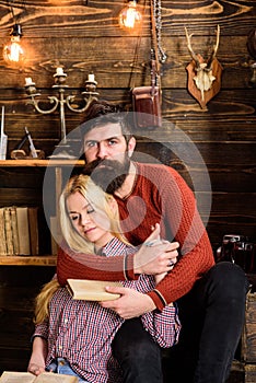 Couple in wooden vintage interior enjoy poetry. Romantic evening concept. Lady and man with beard on dreamy faces hugs