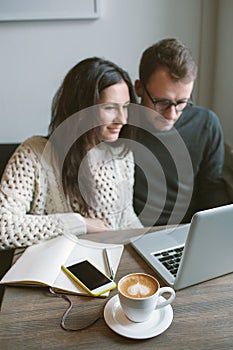 Couple working in cafe with laptop, smartphone and coffee
