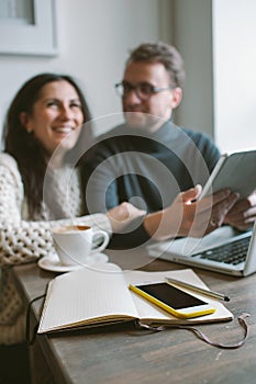 Couple working in cafe with tablet, laptop, smartphone, notepad