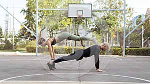 Couple working out on a sportsground, doing a straight-arm plank exercise