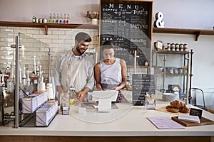 Couple working together at the till in a coffee shop