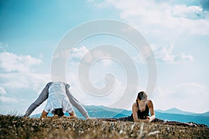 Outdoor shot of couple doing yoga exercise at the hill