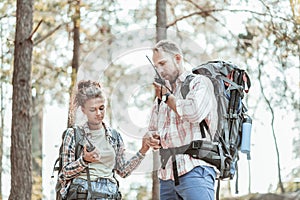 Couple of young backpackers using their pagers after being lost in forest